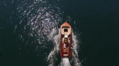 Kahverengi küçük motorlu tekne denizde yüzer, köpük izi bırakır. Yüksek kalite 4k görüntü