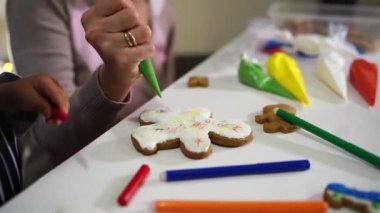 Küçük kız, annesine parmağıyla Noel kurabiyelerine krema sürdüğü yeri gösteriyor. Yüksek kalite 4k görüntü