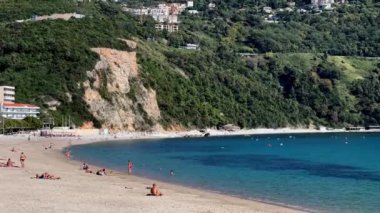 Turistler mavi denizin yakınındaki kumlu bir plajda güneşleniyorlar. Yüksek kalite 4k görüntü