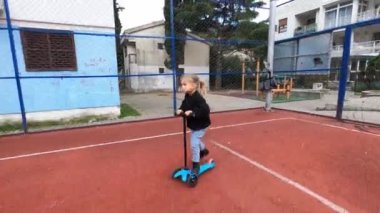 Küçük kız basketbol sahasında scooter kullanıyor. Yüksek kalite 4k görüntü