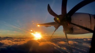 Bulutların üzerinde batan güneşin arka planına doğru uçan bir uçağın pervanesi. Yüksek kalite 4k görüntü