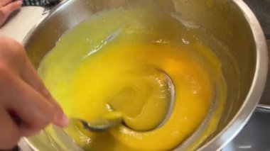 Ev hanımı kaşıkla yumurta sarısını kasede karıştırıyor. Yüksek kalite 4k görüntü