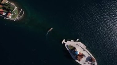 Gospa od Skrpjela adaları ve körfezin karşısındaki Aziz George adaları arasında bir tekne yelken açar. Drone. Yüksek kalite 4k görüntü