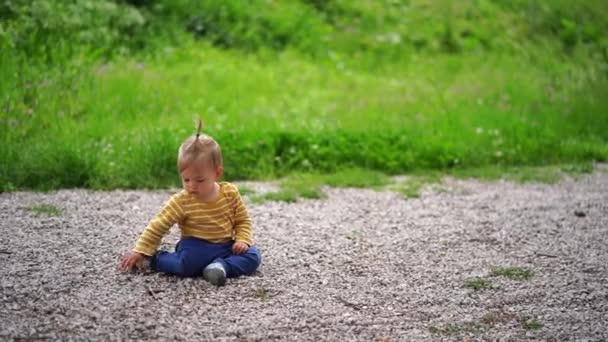 小女孩坐在公园的石子路上玩鹅卵石 高质量的4K镜头 — 图库视频影像