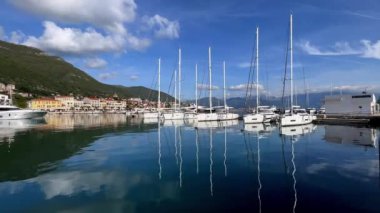 Dağların eteğindeki renkli evlerin arka planında yatları olan Marina. Yüksek kalite 4k görüntü