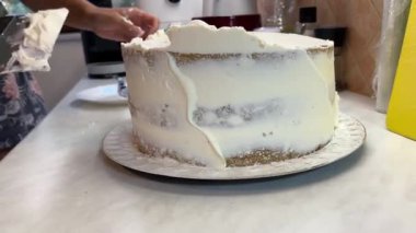 Kadın, kremayı bir spatulayla birlikte pastanın yüzeyine eşit olarak yayıyor. Yüksek kalite 4k görüntü