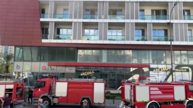 Yanıp sönen ışıkları olan kırmızı itfaiye araçları dumanı tüten bir binanın yanında duruyor. Yüksek kalite 4k görüntü