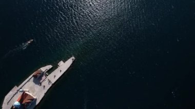 Tekne, Kotor Körfezi 'ndeki Kayalıklardaki Meryem Kilisesi' nin yanından geçiyor. Drone. Yüksek kalite 4k görüntü