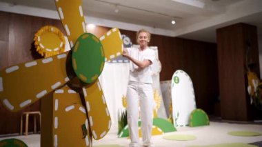 Sahnedeki kadın oyuncak bir yel değirmeninin çarkını döndürür ve kapıdan bir çanta çıkarır. Yüksek kaliteli FullHD görüntüler