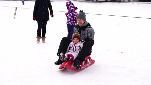 ママと小さな女の子は雪の丘を下りている 高品質の4K映像 — ストック動画