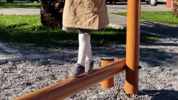 Küçük Kız Kiriş Boyunca Dikkatlice Yürüyor Oyun Alanındaki Korkuluklara Tutunarak — Stok video