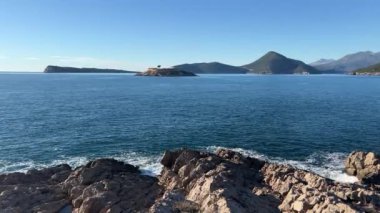 Kayalık kıyıdan, denizdeki adaya, dağ sırasının arka planına bakın. Yüksek kalite 4k görüntü