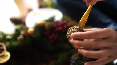 Kadın yeni yıl çelengi için fırçayla altın boya sürüyor. Yüksek kalite 4k görüntü