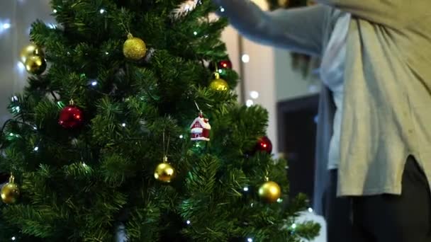 年轻的女人把玩具挂在圣诞树的绿枝上 高质量的4K镜头 — 图库视频影像