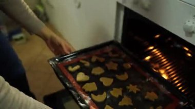 Ev hanımı fırına şekilli Noel kurabiyeleriyle birlikte bir yemek tepsisi koyar. Yüksek kalite 4k görüntü