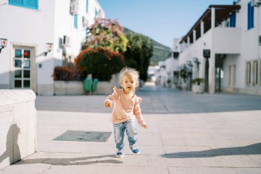 Küçük kız evlerin yakınındaki kaldırım boyunca koşuyor. Yüksek kalite fotoğraf