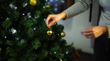 Ev hanımı evdeki köknar dallarına altın toplar asıyor. Yüksek kalite 4k görüntü