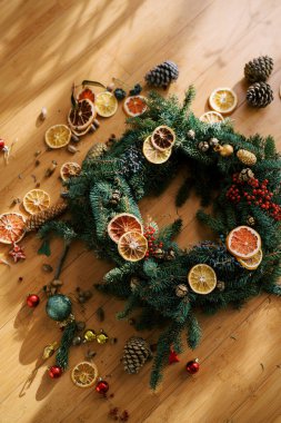 Kurumuş meyve ve koni parçalarıyla çevrili Noel çelengi ahşap bir zeminde yatıyor. Üst Manzara. Yüksek kalite fotoğraf