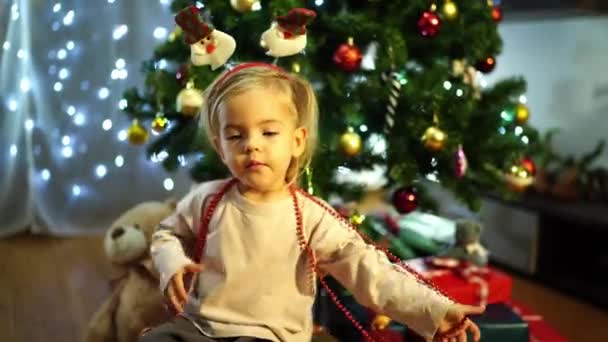 Little Girl Festive Headband Babbles While Sitting Decorated Christmas Tree Royalty Free Stock Footage