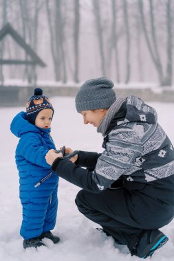 Annem tulumlu, yanında çömelmiş küçük bir kıza eldiven takıyor. Yüksek kalite fotoğraf