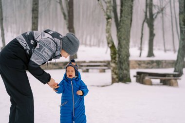 Annem karlı bir ormanda ağlayan küçük bir kızın eline yaslandı. Yüksek kalite fotoğraf