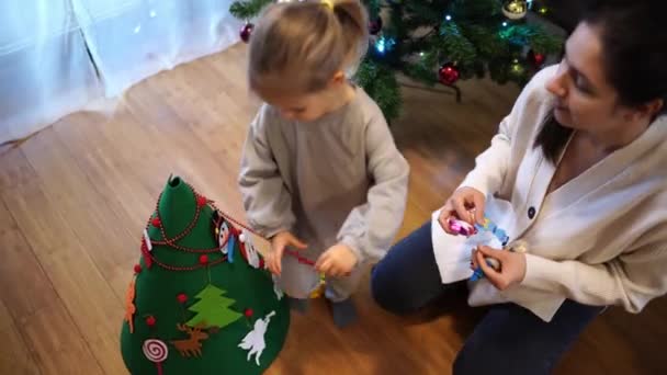 Little Girl Decorates Toy Christmas Tree Garland Next Her Mother Stock Video