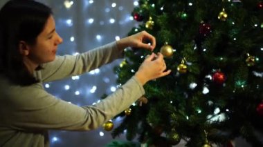 Ev hanımı renkli taşaklı bir Noel ağacına çan asıyor. Yüksek kalite 4k görüntü