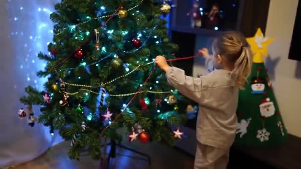 小女孩把五彩缤纷的珠子挂在圣诞树的枝头上 高质量的4K镜头 — 图库视频影像