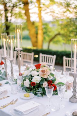 Renkli bir buket çiçek yanan mumların yanındaki şenlik masasında duruyor. Yüksek kalite fotoğraf