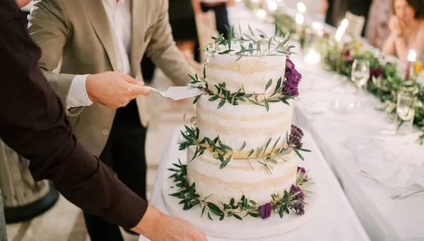 Men take a piece of wedding cake on the table with a spatula. Cropped. Faceless. High quality photo