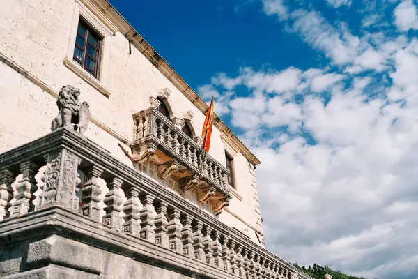 Flag on a flagpole hangs on a balcony with a stone carved balustrade of an ancient building. High quality photo