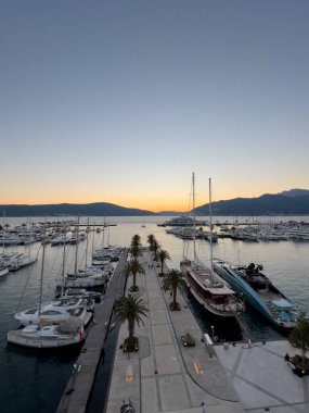Yatlar, körfezde palmiye ağaçlarıyla iskelede, gün batımının arka planında, dağların üzerinde duruyor. Yüksek kalite fotoğraf