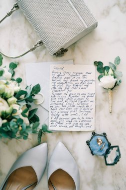 Evlilik yemini gelin buketi ve yaka çiçeğinin yanındaki mermer bir masada yatıyor. Yüksek kalite fotoğraf