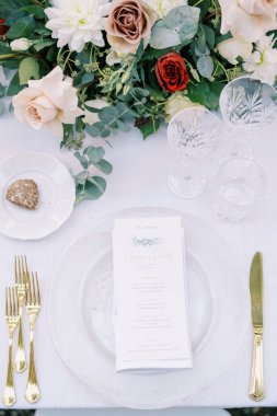 Davetiye, çiçeklerin yanındaki şenlik masasında bir tabakta duruyor. Üst Manzara. Yüksek kalite fotoğraf