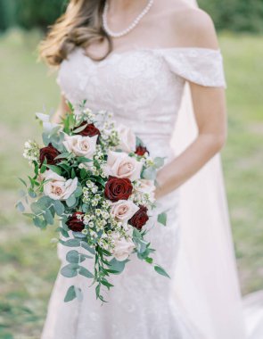 Elinde bir buket çiçekle gelin parkta yürür. Kırpılmış. Yüzsüz. Yüksek kalite fotoğraf