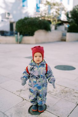 Tulumlu küçük bir kız ve evin avlusundaki fayansta duran bir şapka. Yüksek kalite fotoğraf