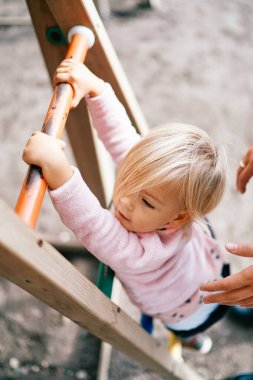 Annem çocuk parkında merdivenlerden çıkan küçük bir kızı destekliyor. Kırpılmış. Yüksek kalite fotoğraf