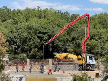 İnşaat alanındaki işçiler temeli beton bir pompayla döker. Yüksek kalite fotoğraf