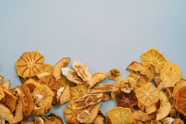 Kurumuş meyve parçaları mavi arka planda, alt kenar boyunca uzanır. Yüksek kalite fotoğraf