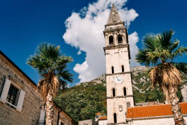 Aziz Niklas Kilisesi 'nin çan kulesi. Yeşil dağların arkasında antik evlerin arasında bir saat var. Perast, Karadağ. Yüksek kalite fotoğraf