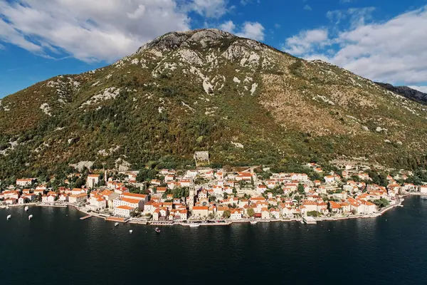 Dağın eteğindeki kilisenin çan kulesiyle Perast 'ın dolambaçlı kıyı şeridi. Karadağ. Drone. Yüksek kalite fotoğraf