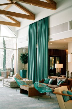 Otelin kanepeleri, hasır sandalyeleri ve panoramik kemerli pencerenin yanındaki masaları olan salonu. Yüksek kalite fotoğraf