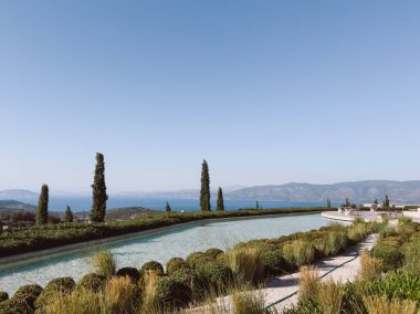 Dağların arkasına karşı denizin üzerinde uzun bir havuz. Amanzoe Oteli, Yunanistan. Yüksek kalite fotoğraf