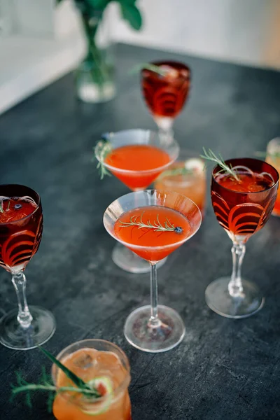 Glasses with red cocktails decorated with green twigs and berries stand on the table. High quality photo
