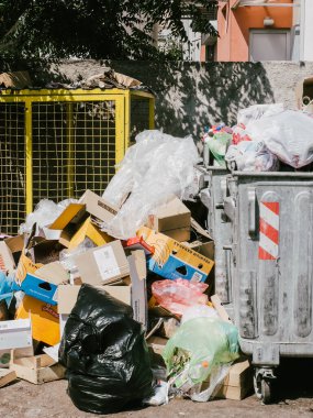 Boş karton kutular ve plastik atık taşan bir çöp kutusunun yanında yatıyor. Yüksek kalite fotoğraf