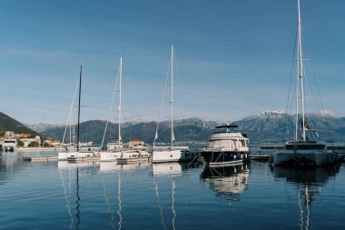Rıhtımda, dağların arka planına karşı duran yelkenli yatları var. Yüksek kalite fotoğraf