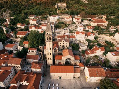 Aziz Niklas Kilisesi 'nin uzun çan kulesi ve eski evlerin kırmızı çatıları arasında bir saat. Perast, Karadağ. Drone. Yüksek kalite fotoğraf