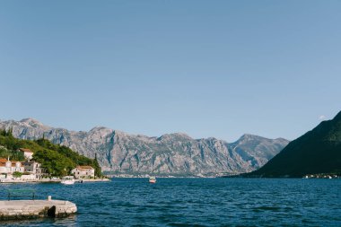 Tekneler Perast kıyısından yüksek bir dağ sırasının arka planına doğru yelken açarlar. Karadağ. Yüksek kalite fotoğraf