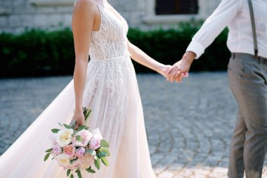 Gelin ve damat eski bir malikanenin önünden el ele geçerler. Kırpılmış. Yüzsüz. Yüksek kalite fotoğraf