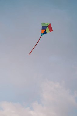 Gökkuşağı uçurtması bulutlu gökyüzünde yükselir. Yüksek kalite fotoğraf